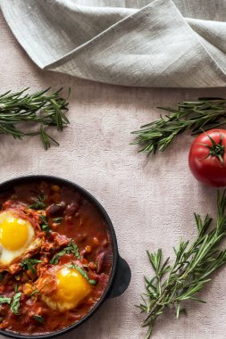 Shakshuka bir sos domates, acı biber, soğan ve baharatlar siyah bir dökme demir tava üzerinde kızarmış yumurta, lezzetli bir yemektir. Domates, pan, peçete ve parlak sabah güneş ışınlarının biberiye.