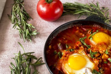 Shakshuka bir sos domates, acı biber, soğan ve baharatlar siyah bir dökme demir tava üzerinde kızarmış yumurta, lezzetli bir yemektir. Domates, pan, peçete ve parlak sabah güneş ışınlarının biberiye.