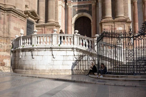 Malaga, Spagna, febbraio 2019.Due ragazze si rilassano sui gradini di marmo della famosa cattedrale incarnata di Malagan e mangiano gelato. La Cattedrale di Malaga è l'attrazione principale della città. Interruzione del viaggio . — Foto Stock