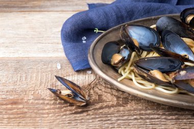 Midyeile spagetti, eski ahşap masanın üzerinde orijinal tabakta baharatlı soslu domates. İstiridye Mytilus yakın çekim. İtalyan makarnası. Romantik bir akşam yemeği için bir tabak.