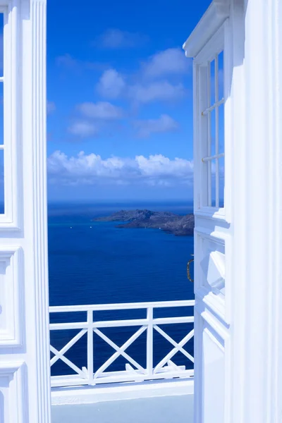 Puerta abierta luz de madera blanca. Detrás de la puerta hay un hermoso mar turquesa y montañas. Mañana soleada en la isla griega de Santorini . —  Fotos de Stock