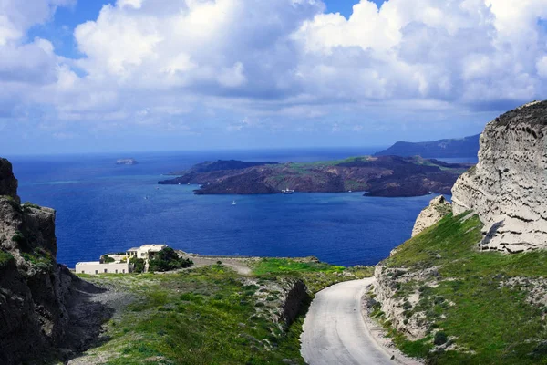 Καλοκαιρινό ηλιόλουστο πρωινό στο νησί της Σαντορίνης, Ελλάδα. Γαλάζια θάλασσα, γαλάζιος ουρανός με σύννεφα στο φόντο του νησιού. Ταξίδια σε ευρώ. Δρόμος προς τη θάλασσα. — Φωτογραφία Αρχείου