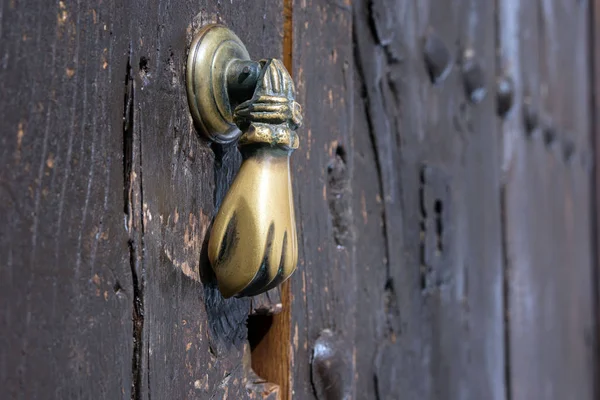 Punho da porta de bronze velho na forma de uma mão. Porta de madeira marrom de uma casa na cidade espanhola de Ronda . — Fotografia de Stock