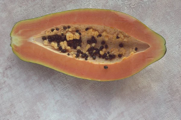 Papaya (Carica papaya) is an exotic, tasty, sweet fruit. Melon (bread) tree fruit against a pink background. Half. Papaya seeds are edible and can be a cure. Close-up. — Stock Photo, Image