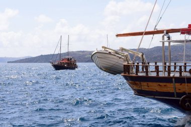 Yunanistan 'ın eski kenti Fira' nın eski limanında tahta bir zevk teknesinin pruvasında beyaz bir kurtarma botu. Dağların, denizin ve gemilerin güzel manzarası, Santorini Adası, Yunanistan.