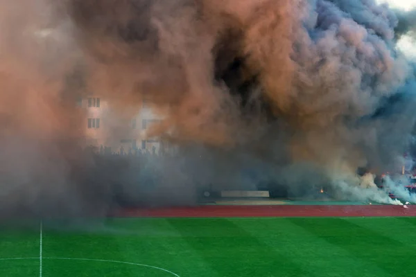 Kolor grubych dymu na boisku piłki nożnej. Fani piłki nożnej stworzył niepokojów podczas gry i rzucił bomby dymne na polu z kolorowym dymem. Naruszenie porządku publicznego, zagrożenie życia. — Zdjęcie stockowe