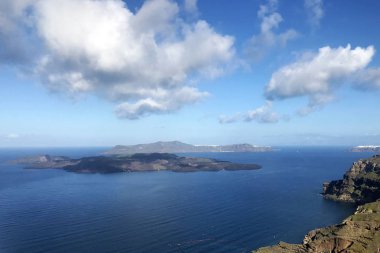 Çiçeklerle kaplı deniz, yatlar ve dağların güzel manzarası. Sıcak güneşli bir günde Santorini Yunan adası. Avrupa'nın pitoresk yerlere seyahat. Ege Denizi'ndeki Kiklad adaları.