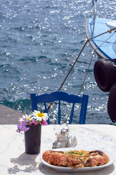 Вкусный ланч у моря. Белая тарелка спагетти с огромными омарами на гриле. Путешествие в Санторини, Греция. Старый порт Фира. Уютный семейный ресторан. Вкусное путешествие . — стоковое фото