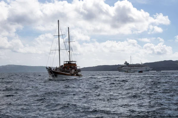 Santorini, Grecja, 2019 kwietnia. Łódź przyjemności z masztów na molo w starym porcie w Fira, Grecja, Santorini. Turyści przygotowują się do pojechać na molo. Spacer po morzu. Wycieczka do euro. — Zdjęcie stockowe