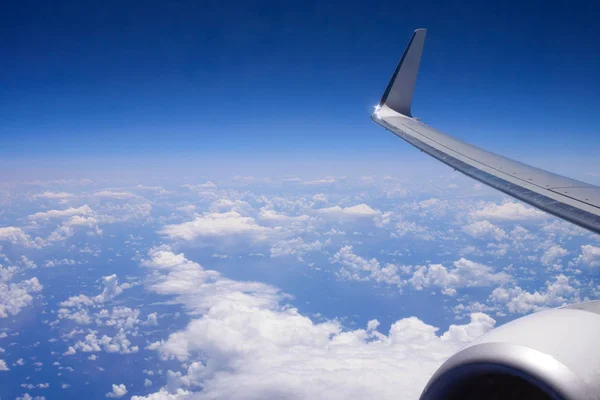 Nuages blancs et duveteux dans le ciel bleu sous l'aile de l'avion. Photos des nuages du hublot passager. Fond photo . — Photo