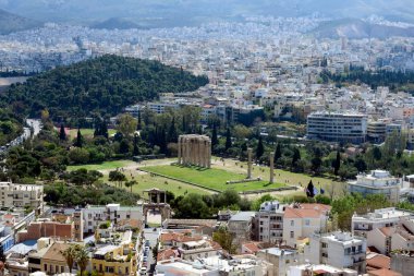 Antik Yunan kalıntıları, yemyeşil çimenlerin ortasındaki harabeler. Akropolis, Atina, Yunanistan. Sıcak güneşli bir günde Akropolis'in yamaçlarından Atina'nın ve Olimpiyat Zeus Tapınağı'nın güzel manzarası.