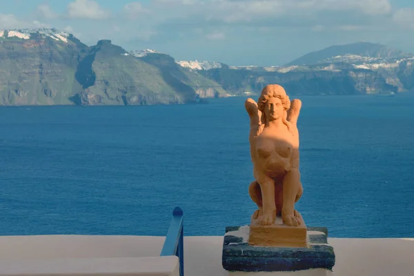 Schöne insel santorini, griechenland. griechische Skulptur der Sphinx auf der Insel Santorini vor dem Hintergrund des Meeres. die stadt oia auf der insel santorini. Sonnenuntergang. Griechenland-Reise. — Stockfoto