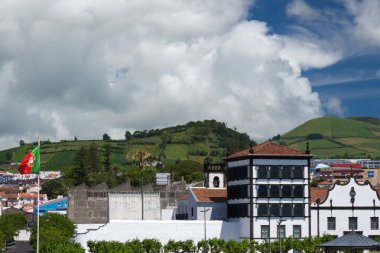 Dağların güzel görünümü, evlerin çatıları ve Ponta Delgada şehrinin sokakları, Portekiz. Şehrin üzerinde gri yağmur bulutları. Azores, San Miguel adası.