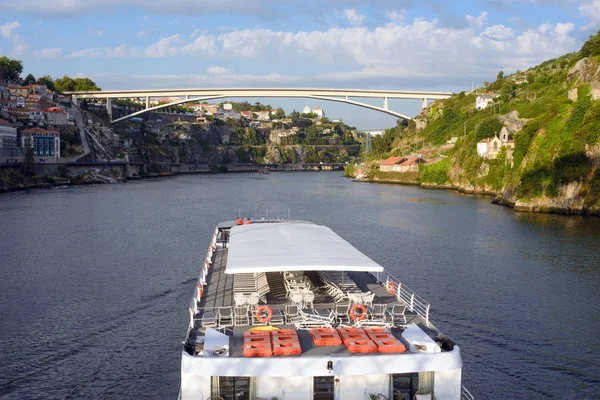 Prachtig uitzicht op de rivier de Douro in de stad Porto, Portugal. Een rivier, een brug en een grote White Pleasure cruise boot in het licht van de ondergaande zon. Een interessante reis naar Portugal. — Stockfoto