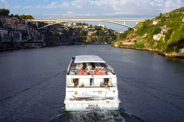 Porto, Portugal, 2019 juni. Prachtig uitzicht op de rivier de Douro in de stad Porto, Portugal. Een rivier, een brug, daken van huizen en een grote White Pleasure cruise boot in het licht van de ondergaande zon. — Stockfoto