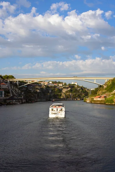 Porto, Portugal, 2019 juni. Prachtig uitzicht op de rivier de Douro in de stad Porto, Portugal. Een rivier, een brug, daken van huizen en een grote White Pleasure cruise boot in het licht van de ondergaande zon. — Stockfoto