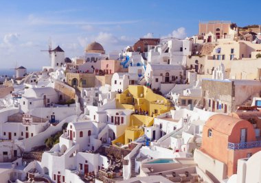 Santorini, Yunanistan, Nisan 2019. Santorini adasında bir yamaç üzerinde Beyaz geleneksel Yunan evleri. Turistler gün batımını bekliyor. Oia şehrinde gün batımı, Santorini.