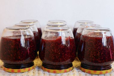 Beyaz havlu üzerinde ahududu reçeli olan kavanozlar. Evde ahududu reçeli yaparız. Canning. Hasat konfeksiyonu.