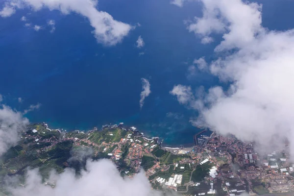 Uçağın porthole gelen deniz ve San Miguel adasının sahil güzel görünümü. Atlantik Okyanusu üzerinde beyaz bulutlar. Azores, Portekiz.
