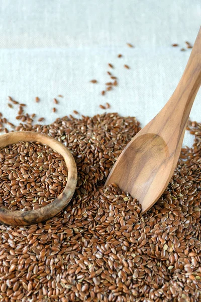 Flax seeds Linum usitatissimum - a useful and medicinal product. Close-up. Spoon and plate of natural olive tree among flax seeds