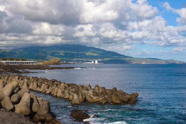 Tetrápodes de concreto armado junto ao mar na cidade de Ponta Delgada protegem a costa das ondas. Belas vistas do mar, montanhas, nuvens e quebra-mares. Ilha de San Miguel, Açores, Portugal . — Fotografia de Stock