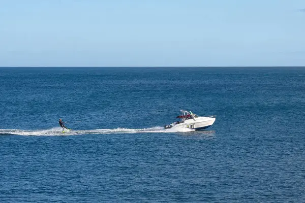 Portugal, Ponta Delgada, juin 2019. Un jeune homme en costume noir faisant du ski nautique après un bateau au large de Ponta Delgada. Île de San Miguel. Açores. Loisirs en mer . — Photo