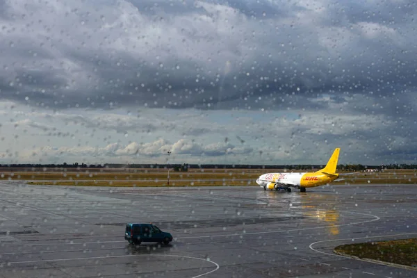 Kiev, Ucrânia, setembro de 2019. Gotas de chuva fluem pelo vidro do aeroporto. Aeroporto em tempo de outono chuvoso. Aeronave solitária DHL Express. Entrega de mercadorias e correio ocorre em qualquer tempo . — Fotografia de Stock