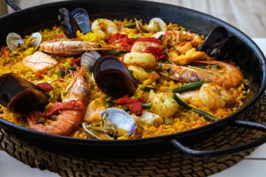  Traditional spanish seafood paella dish in a black pan. Mussels, Amandi and prawns on a pillow of rice. Close-up. Delicious wholesome dinner in a Spanish restaurant on the island of Mallorca. clipart