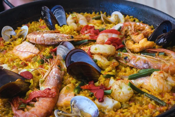  Siyah bir tavada geleneksel İspanyol deniz ürünleri paella çanak. Midye, Amandi ve karidesler pirinç yastığının üzerinde. Close. Mallorca adasında bir İspanyol restoranında lezzetli sağlıklı akşam yemeği.