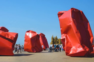 Ostend, Belçika, Ağustos 2019. İnsanlar Ostend'in gezinti yolunda yürüyorlar. Buruşmuş torbaları andıran büyük kırmızı metal yapılar. Belçika. Açık alanda çağdaş sanat. Eğlenceli bir yolculuk.