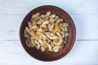 Kahverengi seramik tabakta tuzlanmış karamel ve çıtır çıtır hindistan cevizi cipsi. Hindistan cevizi hamurundan yapılan doğal ürün. Atıştırmak için faydalı bir atıştırmalık. Düzgün beslenme kavramı.