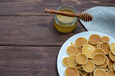 Mısır gevreği krepleri. Beyaz tabakta Amerikan gözlemeleri ve eski ahşap bir masada bal. Lezzetli geleneksel Amerikan kahvaltısı. Yukarıdan görüntüle.