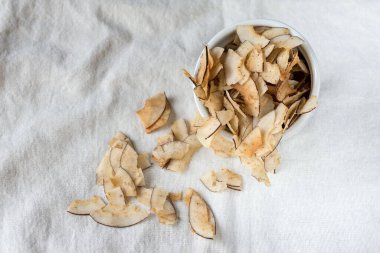 Lezzetli hindistan cevizi cipsleri ve beyaz bir bez parçasında tuzlanmış karamel. Hindistan cevizi hamurundan yapılan doğal ürün. Atıştırmak için faydalı bir atıştırmalık. Düzgün beslenme kavramı.