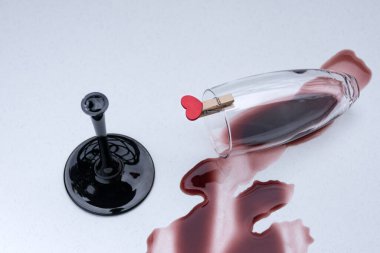 Kırık şarap kadehinde küçük kırmızı bir kalp. Parçalanmış aşk, depresyon ve umutsuzluk kavramı.