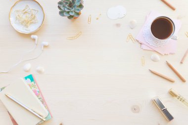 Kadın ev ofis resepsiyon masası pastel tonlarda. Dizüstü bilgisayarlar, fincan kahve ve boşluk ile ışık ahşap arka plan üzerinde süslemeleri ile çalışma alanı. Düz yatıyordu, en iyi görünümü