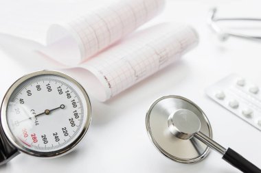 Tıbbi kavramı: steteskop, tonometer, blister ve kardiyogram tablet olan beyaz bir arka plan üzerinde