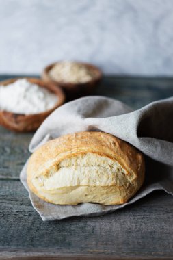 Taze ev yapımı ekmek eski ahşap kurulların arka planda gri kumaş peçete yalan kaplı. Boşluk ile dikey görüntü