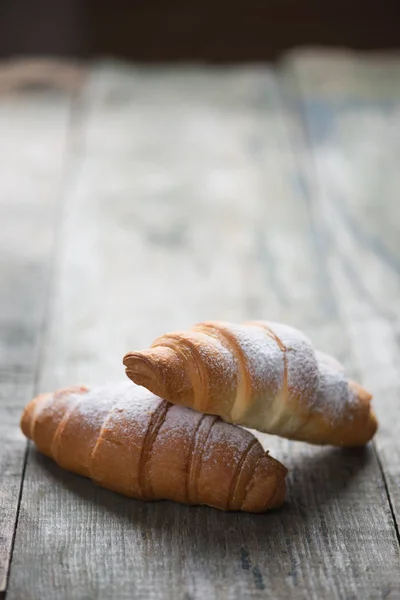 Dvě Čerstvé Croissanty Pokryté Moučkovým Cukrem Lež Pozadí Starých Dřevěných — Stock fotografie