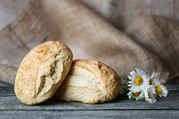 Kaba çuval bezi, boşluk ile arka plan üzerinde iki taze ev yapımı ekmek ciabatta ve papatya çiçekler vardır. Ciabatta geleneği İtalyan fırın üründür