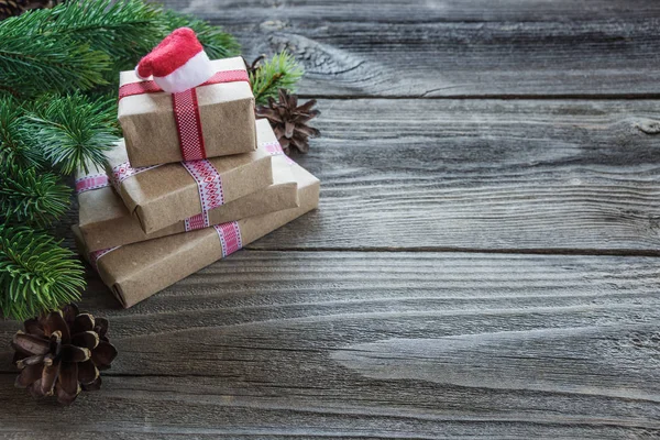 圣诞节组成的松果 云杉分行和堆栈的礼品盒用背景上圣诞老人的帽子的老未上漆的木板上 与复制空间 — 图库照片