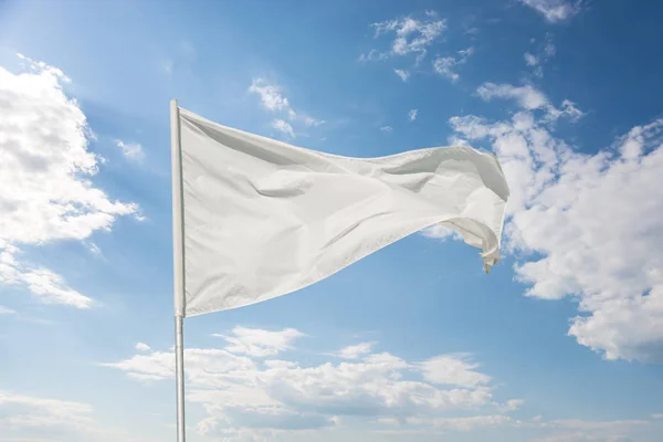 Valkoinen Lippu Sinistä Taivasta Vasten Pilvien Lepattaessa Tuulessa — kuvapankkivalokuva