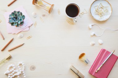 Kadın ev ofis resepsiyon masası pastel tonlarda. Dizüstü bilgisayarlar, fincan kahve ve boşluk ile ışık ahşap arka plan üzerinde süslemeleri ile çalışma alanı. Düz yatıyordu, en iyi görünümü