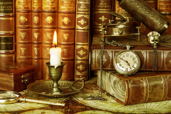 在古色古香的书的背景上 在一个古老的烛台上的复古怀表和燃烧的蜡烛 — 图库照片