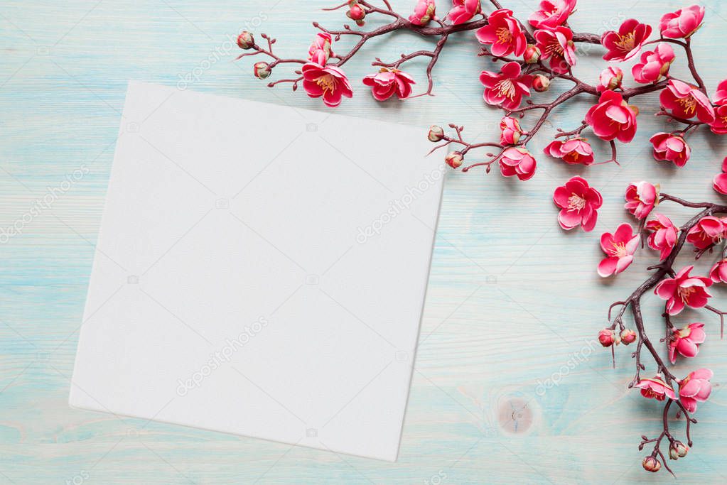 Pink flowers on blue wooden background and paper sheet