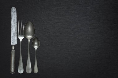 Siyah bir levhada eski bir çatal bıçak.