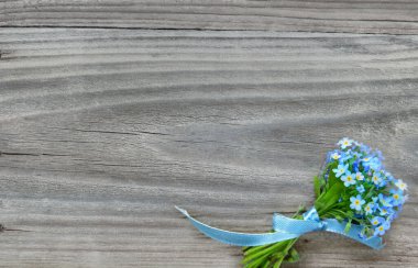Küçük bir buket mavi unutma beni çiçekleri, mavi bir kurdele bağladı, eski ahşap arka planda, kopyalama alanı ile