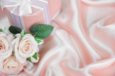 Bir buket pembe gül ve üzerinde pembe ipek kumaştan bir fiyonk olan hediye kutusu. Kopyalama alanı olan tebrik kartı için boşluk