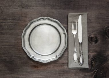 Eski ahşap arka planda antika gümüş çatal bıçak ve antika teneke tabak.