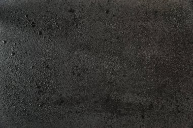 Küçük su damlacıklarıyla kaplı siyah kayanın pürüzlü yüzeyi. Soyut arkaplan