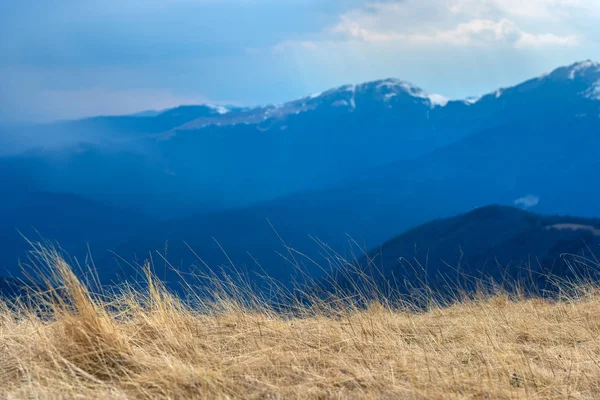 Early spring in the mountains, with peaks still covered with snow. Panoramic view of a natural alpine landscape in a sunny day, with majestic Bucegi mountains in the Carpathians.